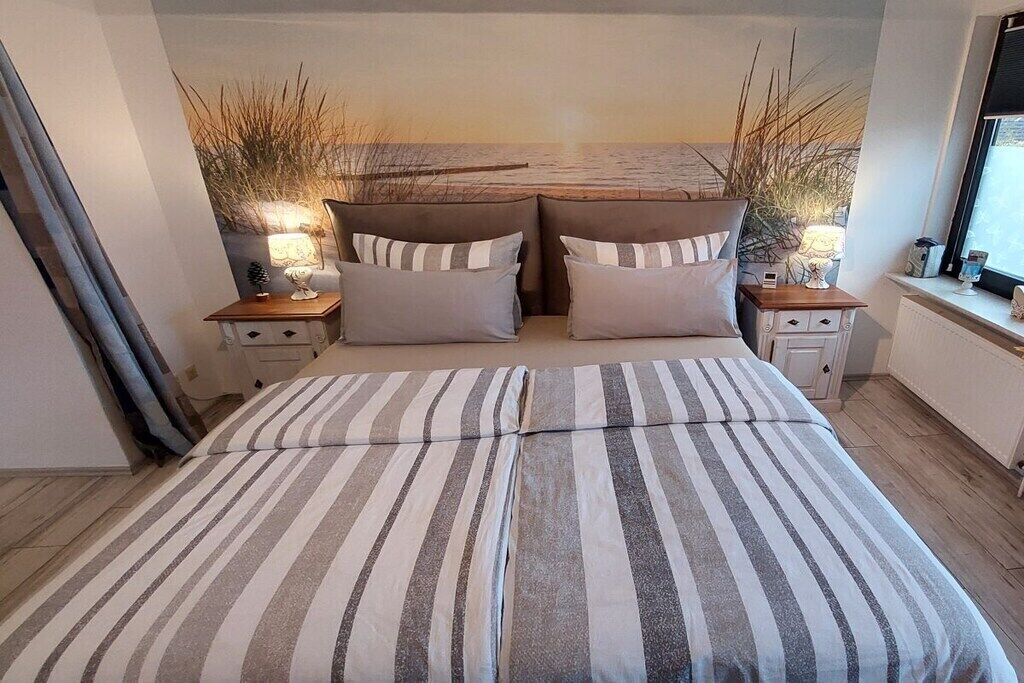 A bedroom with a bed, two bedside tables, a nightstand, a window, and a wall with a textured design.