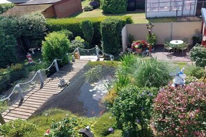 A garden with a wooden bridge, a pond with fish, and a seating area with a table and chairs. - Holiday apartment with 2 bedrooms (Norden)
