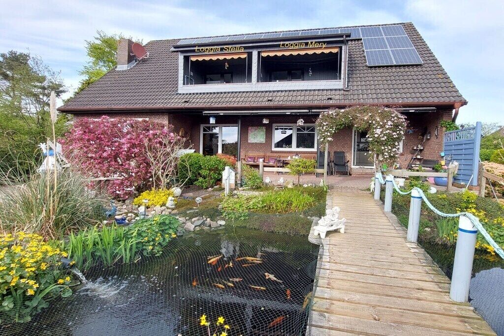 A two-story building with a pond and a wooden deck leading to the entrance.