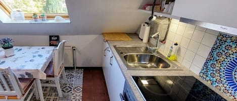 Una cocina compacta con ventana, un lavamanos, una estufa y un comedor con mesa y sillas.