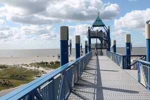 A pier leading to a beach with a lifeguard tower, a clear sky, and a calm sea. - Holiday apartment with 2 bedrooms (Norden)