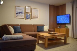Ein modernes Wohnzimmer mit einer Couch, einem Couchtisch und einem Fernseher.