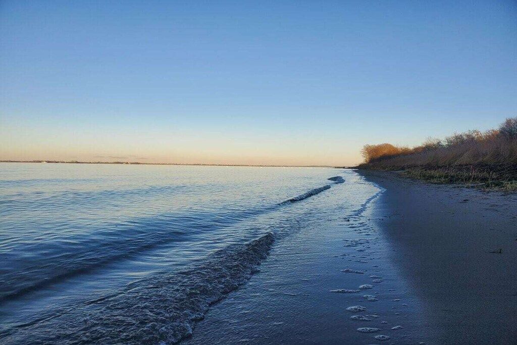 A beach with a clear sky and calm water.