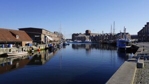 A marina with boats docked, buildings along the water, and a clear sky. - Amber ring 5a|| Zierow (Zierow)