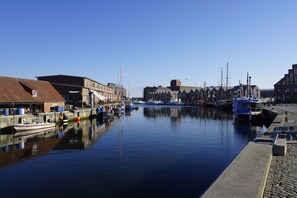 A marina with boats docked, buildings along the water, and a clear sky. - Amber ring 5a|| Zierow (Zierow)