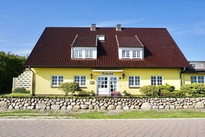 A yellow building with a red roof, a stone wall in front, and a sign that reads 'Lindenhof'. - Lindenhof Holiday Apartment 5 (Wenningstedt-Braderup)