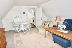 A cozy room with a dining table, chairs, a sofa, and a lamp. - Lindenhof Holiday Apartment 5 (Wenningstedt-Braderup)