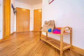 A hallway with wooden flooring, a bench with storage, and two wooden doors. - Holiday apartment in Juliusruh with Wi-Fi (Juliusruh)