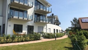 En modern bostadsbyggnad med flera våningar, balkonger, en böjd fasad och en välskött gräsmatta.