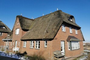 Un edifici tradicional de maó amb teulada de palla i diverses finestres.