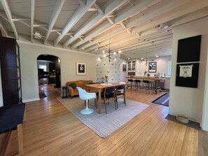 A spacious kitchen with a wooden dining table, chairs, and a hanging light fixture. - The Modern | 3 BR Upscale Retreat 3 Blocks to IU (Bloomington)