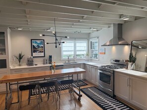 A modern kitchen with white cabinetry, a wooden dining table, and a black and white rug. - The Modern | 3 BR Upscale Retreat 3 Blocks to IU (Bloomington)