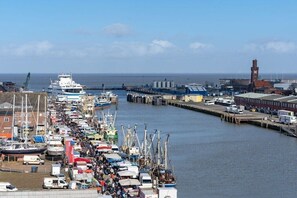 A harbor with boats docked along the piers, a large ship on the left, and a clock tower in the background. - Luca Panorama Apt. 107, 8th floor (Cuxhaven)