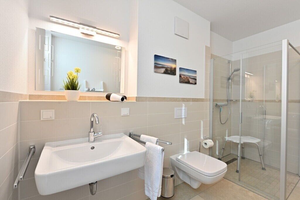 A modern bathroom with a large sink, toilet, and glass-enclosed shower.