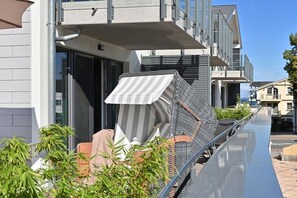 A modern building with a balcony, outdoor seating, and a clear sky. - Holiday apartment in Glowe with swimming pool (Glowe)