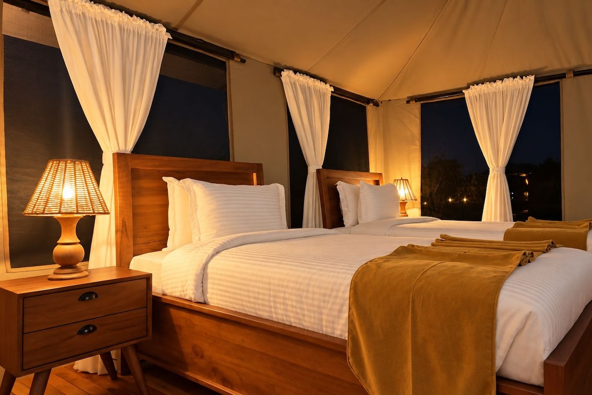 A double bed with white linens, a wooden headboard, and a bedside table with a lamp.