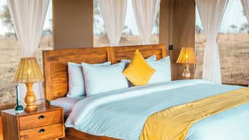 Un lit avec une tête de lit en bois, une literie blanche et bleu clair, et un oreiller jaune. Il y a deux lampes de chevet avec des abat-jour.