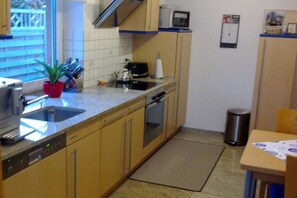 A compact kitchen with a dishwasher, microwave, and a small window. - "House by the Sea" - Ground Floor (Insel Poel, OT Schwarzer Busch)