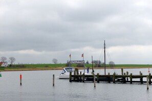 A boat docked at a wooden pier with a sign reading 'Gastlieger Kirchdorf.' - "House by the Sea" - Ground Floor (Insel Poel, OT Schwarzer Busch)