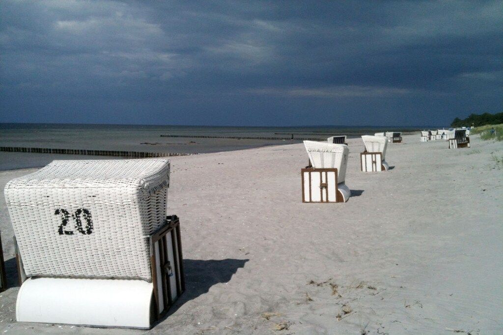 En strand med rader av vita strandstolar och ett vitt parasoll med nummer 20.