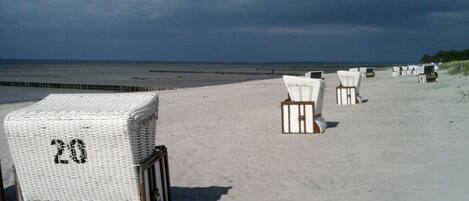 En strand med rader av vita strandstolar och ett vitt parasoll med nummer 20.