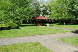 A gazebo with a red roof, surrounded by lush green trees and grass. - Travemünde-Priwall - Anchorage (Lübeck Travemünde)