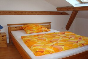 A bedroom with a wooden bed frame, a white mattress, and a patterned blanket. - Hus Klaar Kimming, Wohnung Twee (Hallig Hooge)