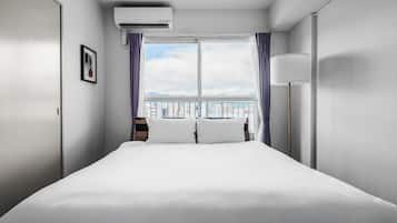 Habitación de hotel con una cama grande, una ventana con cortinas, una mesita de noche y un aire acondicionado de pared.