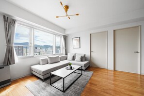 Uma sala de estar moderna com um sofá, uma mesa de centro e vista da cidade por grandes janelas.