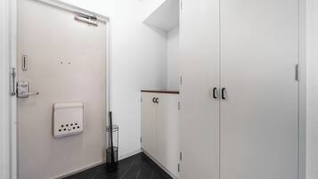 Un pasillo con una puerta blanca, un perchero y un armario de dos puertas.