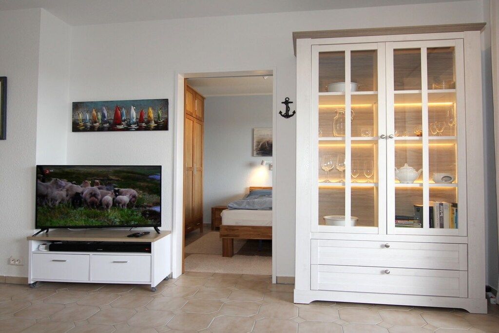 A living room with a television, a cabinet with glass doors, and a painting on the wall.
