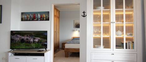 A living room with a television, a cabinet with glass doors, and a painting on the wall.