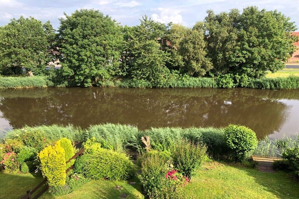 Un jardin aménagé avec un bassin, des haies soigneusement taillées et une variété d’arbustes.