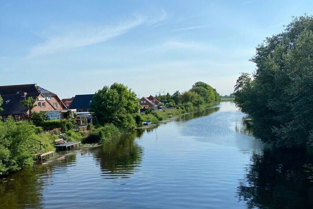 Ein Fluss mit Gebäuden an einer Uferseite und Bäumen an der anderen.