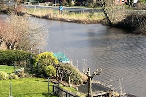 Un río con un puente, un jardín cercado y un edificio con techo verde.