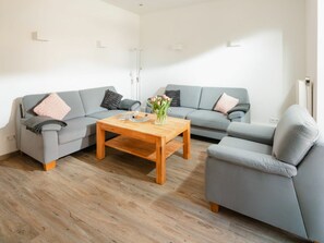 Un salon moderne avec un canapé gris, une table basse en bois et un vase rempli de fleurs.