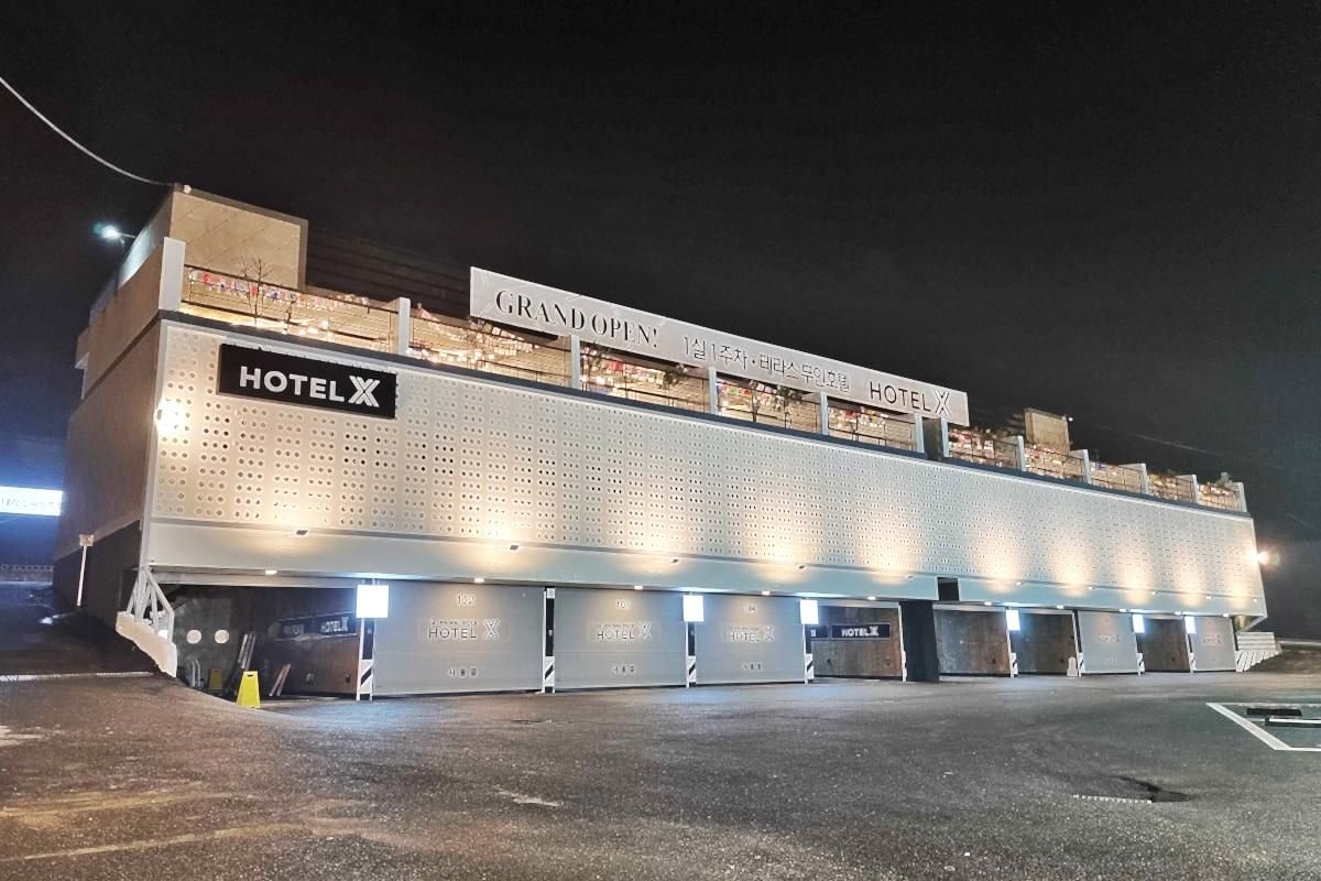 A hotel with a prominent sign for 'GRAND OPEN' and multiple 'HOTEL X' signs.