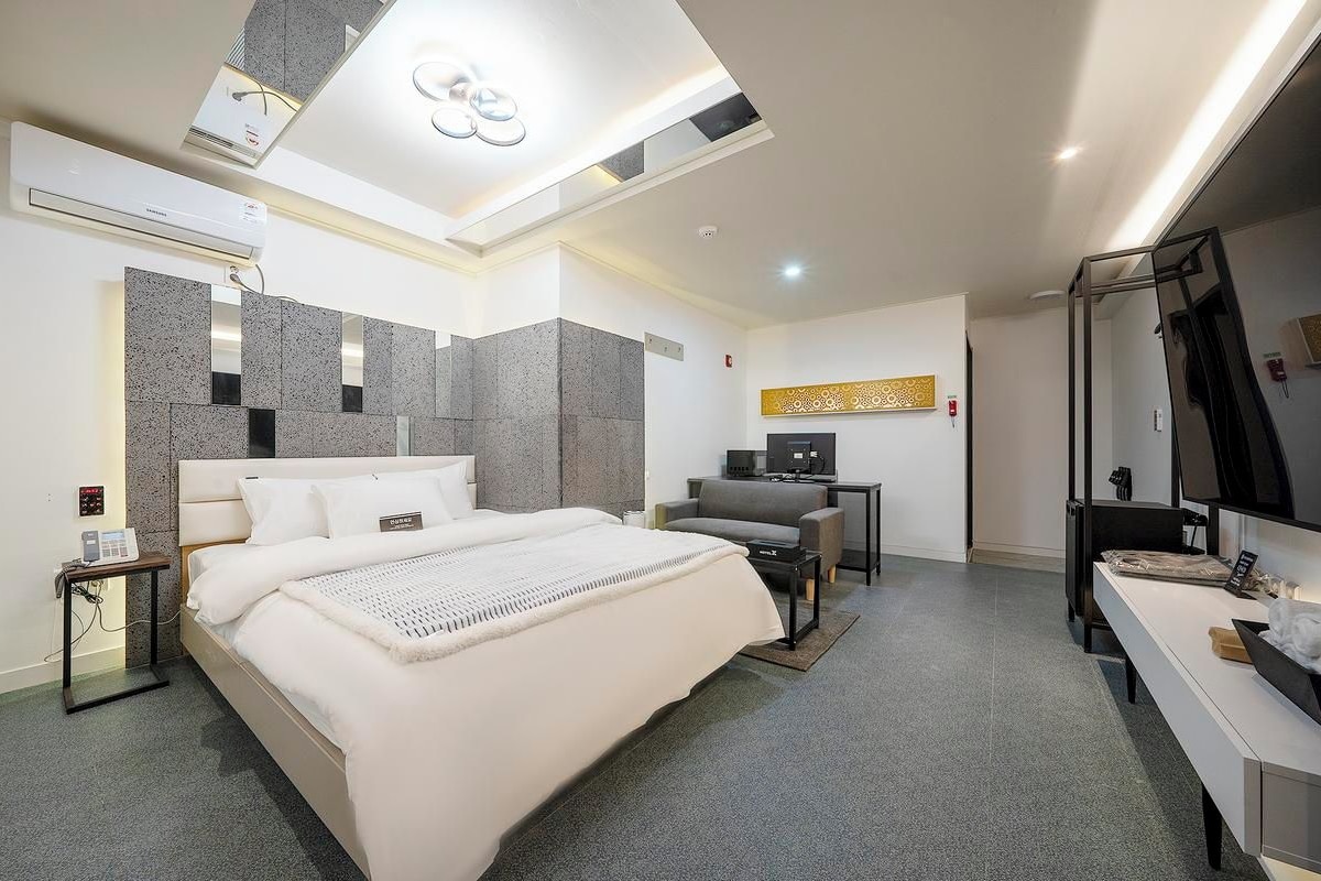 Una habitación de hotel moderna con una cama grande, un escritorio, una silla, un televisor y un baño con espejo.