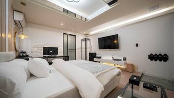 Ein modernes Schlafzimmer mit Bett, Nachttisch, Fernseher und einem an der Wand befestigten Schuhregal.