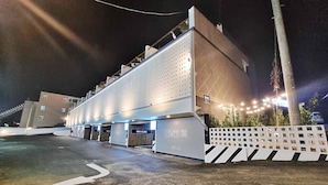 Un hotel con diseño moderno, que cuenta con un amplio estacionamiento y entrada protegida por un portón.