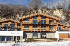 A multi-story lodge with balconies, large windows, and a stone facade. - Superior Holiday Home # 5A with Sauna (Uttendorf)