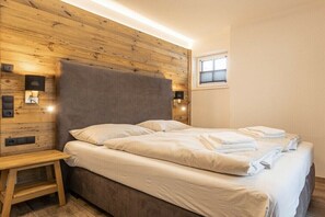 A neatly made bed with white linens and towels, a wooden headboard, and bedside lamps. - Superior Holiday Home # 5A with Sauna (Uttendorf)
