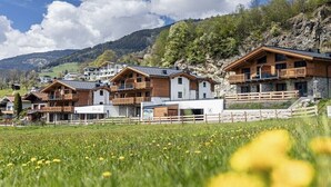 A row of chalet-style buildings with balconies, set against a mountainous backdrop. - Superior Holiday Home # 3B with Sauna (Uttendorf)