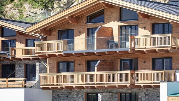A multi-story building with balconies, large windows, and a stone facade. - Superior Holiday Home # 3B with Sauna (Uttendorf)