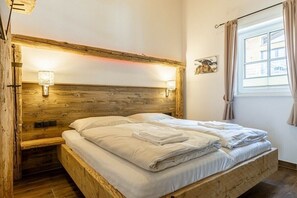 Ein hölzernes Bett mit Kopfteil, zwei Nachttischlampen und einem Fenster mit Vorhängen.