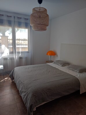 A bedroom with a bed, a lamp, and a window with curtains.