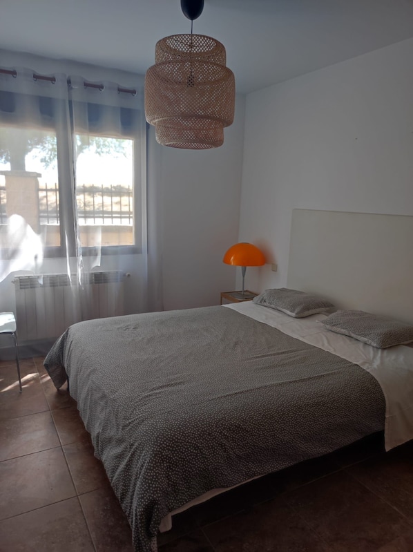A bedroom with a bed, a lamp, and a window with curtains.