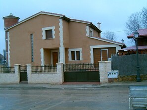 A two-story building with a beige facade, a gated entrance, and a chimney.