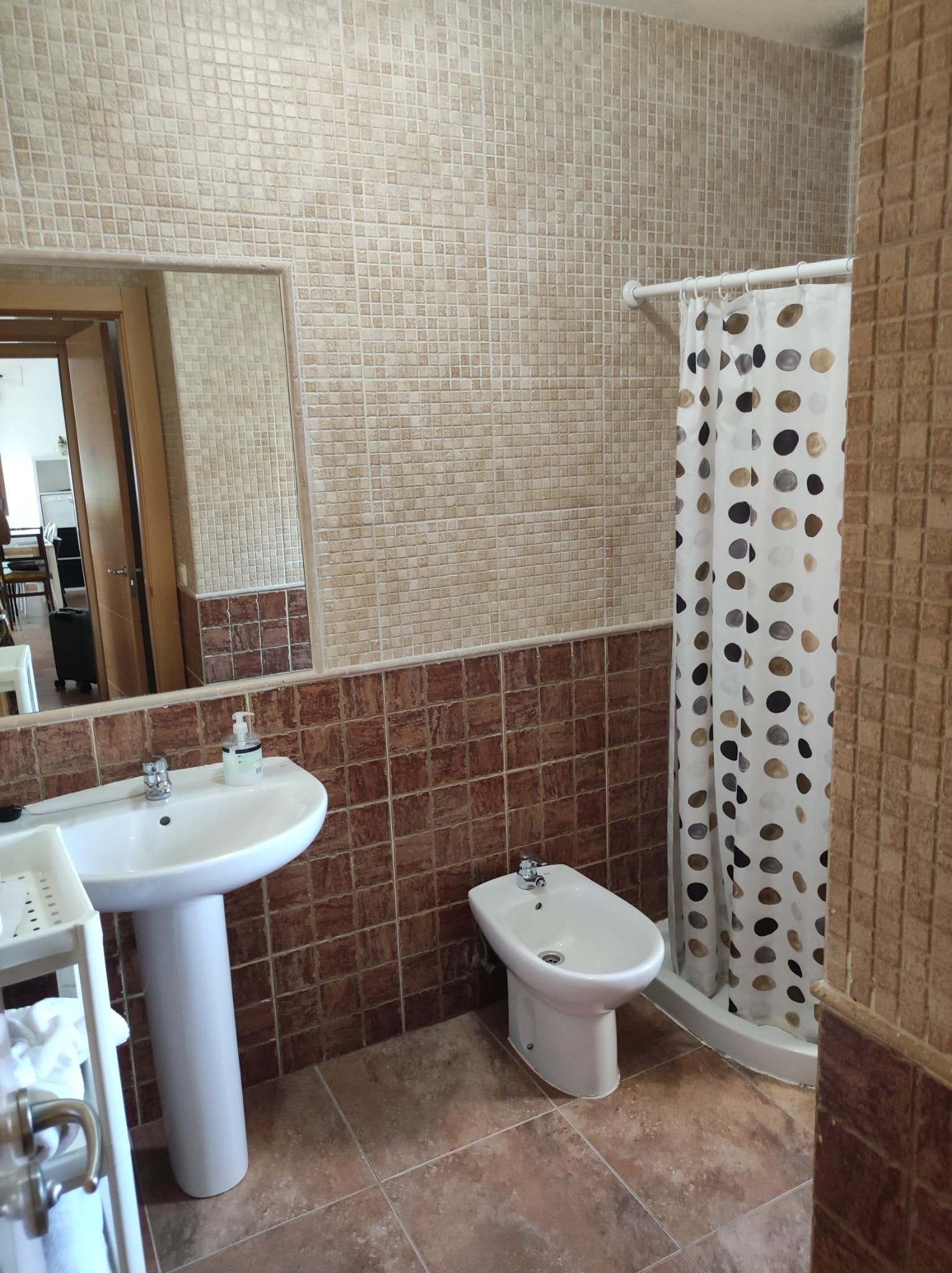 Een badkamer met een wastafel, bidet en douchegordijn.