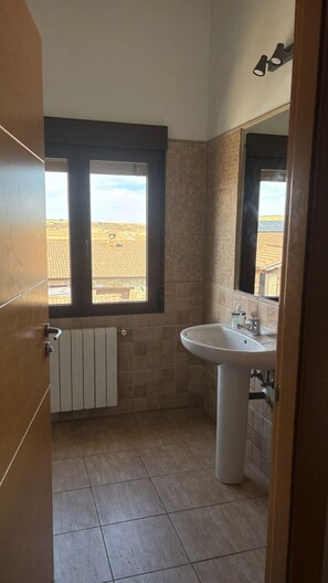 Un baño con ventana, lavabo y radiador.